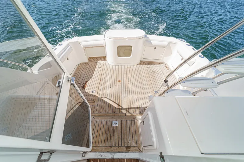 Slide: The Image of 2006 Riviera 33 Open Flybridge boat deck with teak flooring, surrounded by ocean water. - 4