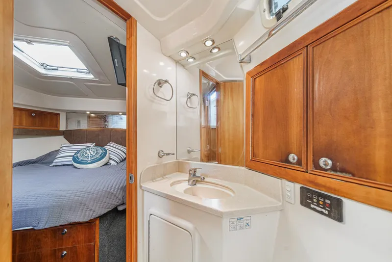 Slide: The Image of 2006 Riviera 33 Open Flybridge interior with bedroom and bathroom, featuring wood cabinetry and modern fixtures. - 6