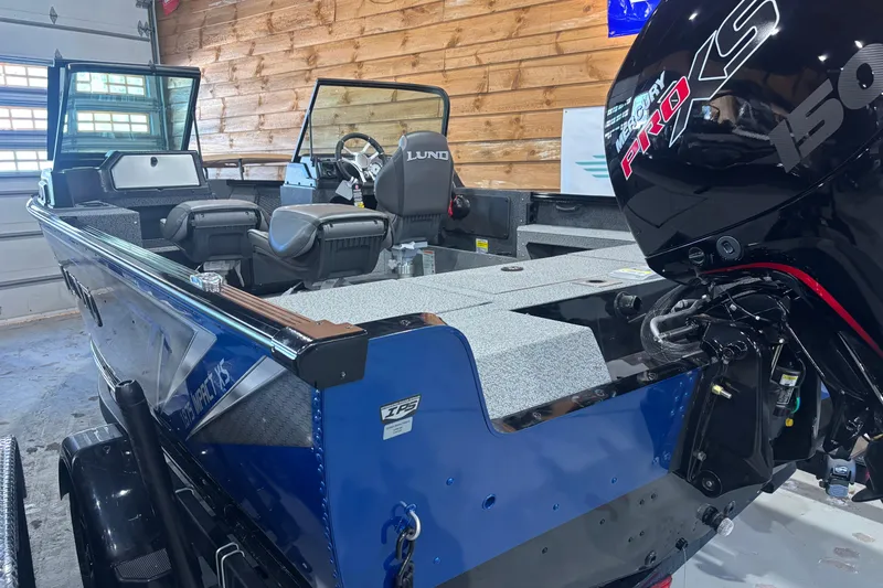 Slide: The Image of 2026 Lund 1875 Impact XS boat with Mercury Pro XS engine in a wooden garage. - 2