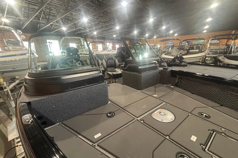 Slide: The Image of 2026 Lund 1875 Impact XS boat interior in showroom with steering console and seating. - 7