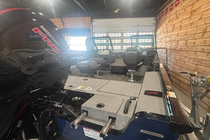 Slide: The Image of 2026 Lund 1875 Impact XS boat interior with Mercury Pro XS engine in a wooden garage. - 9