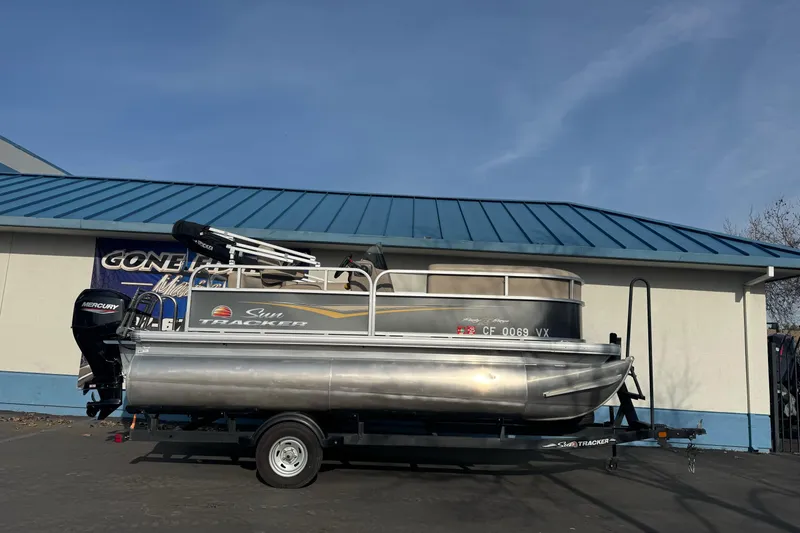 The Image of 2024 Sun Tracker Party Barge 16 DLX pontoon boat on trailer, parked outdoors. - 1