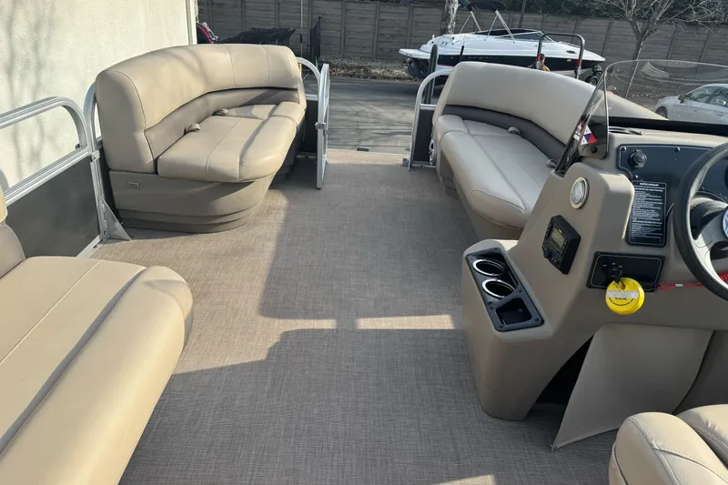 Slide: The Image of 2024 Sun Tracker Party Barge 16 DLX interior with beige seating and steering console. - 11