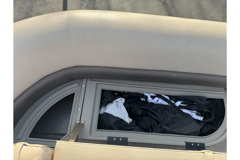 Slide: The Image of 2024 Sun Tracker Party Barge 16 DLX storage compartment with seating and gear inside. - 15