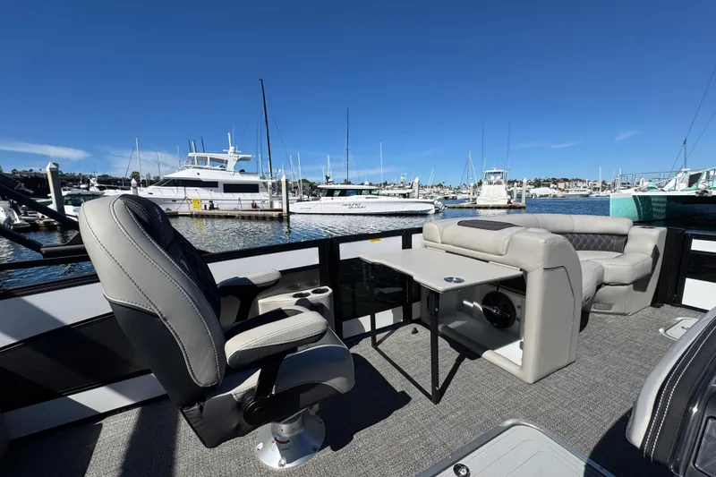 Slide: The Image of Luxurious 2026 Barletta Lusso 23UC pontoon boat interior with plush seating at marina. - 34