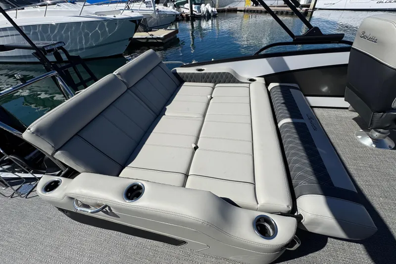 Slide: The Image of 2026 Barletta Lusso 23UC boat interior with luxurious seating and cup holders at a marina. - 56