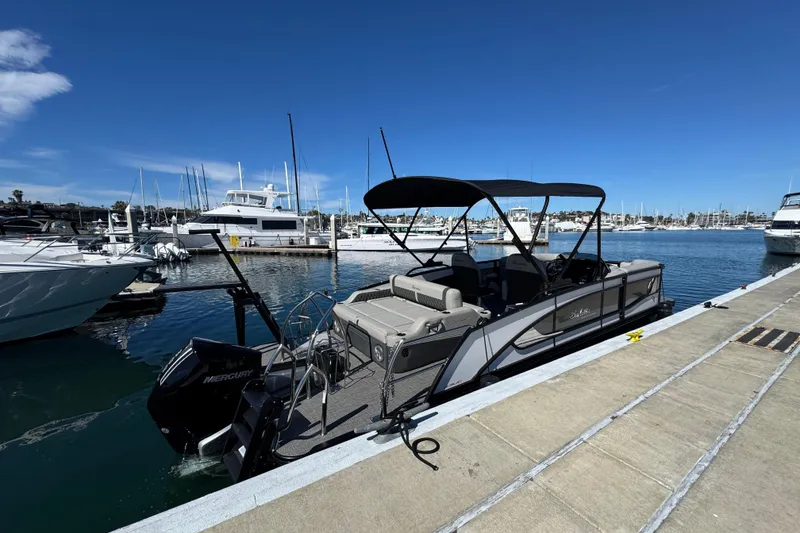 Slide: The Image of 2026 Barletta Lusso 23UC pontoon boat docked at a marina under clear blue skies. - 69