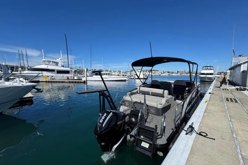 Slide: The Image of 2026 Barletta Lusso 23UC pontoon boat docked in a marina under clear blue skies. - 70