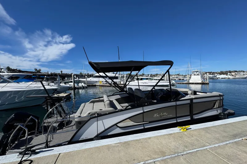 Slide: The Image of 2026 Barletta Lusso 23UC pontoon boat docked at a marina under clear blue skies. - 71