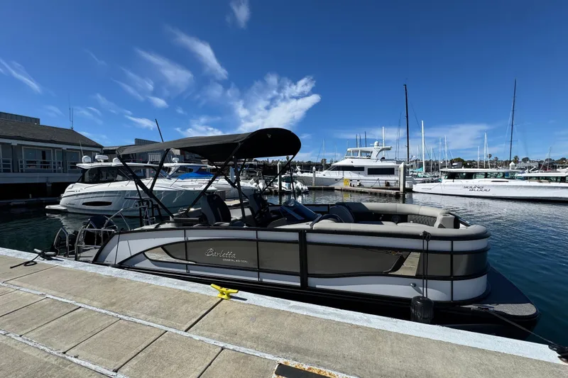 Slide: The Image of 2026 Barletta Lusso 23UC pontoon boat docked at a marina under a clear blue sky. - 73