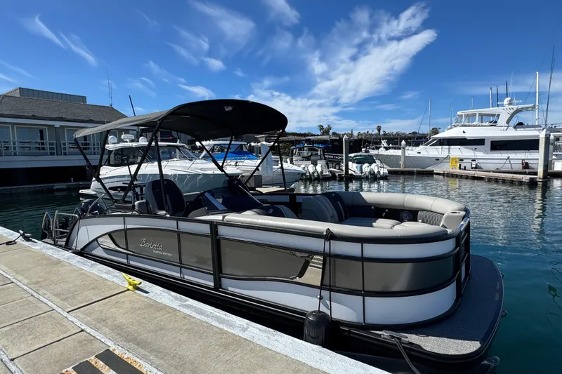 Slide: The Image of 2026 Barletta Lusso 23UC pontoon boat docked at a marina under a clear blue sky. - 74