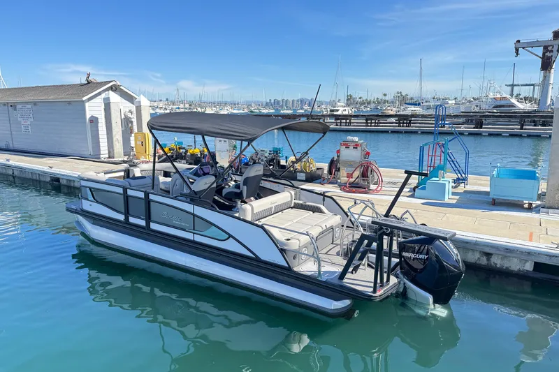 Slide: The Image of 2026 Barletta Lusso 23UC pontoon boat docked at a marina under clear blue skies. - 81
