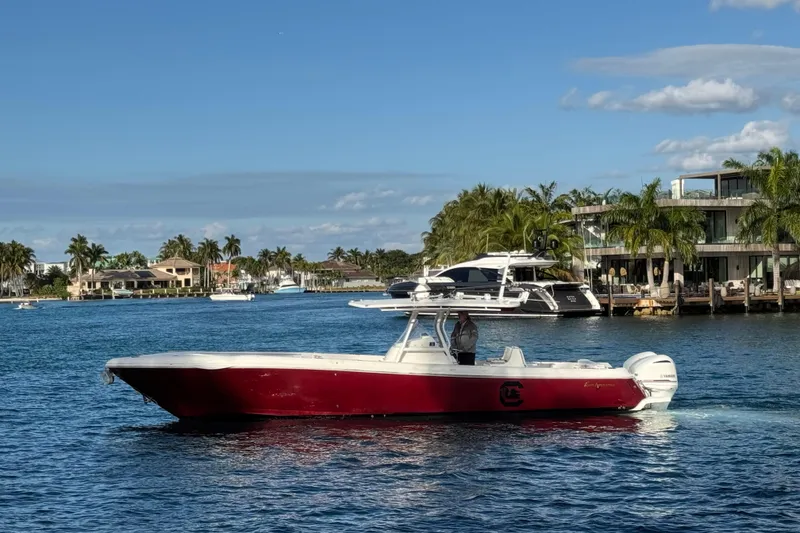 The Image of 2017 Intrepid 375 Center Console boat cruising on a sunny waterfront with palm trees. - 0