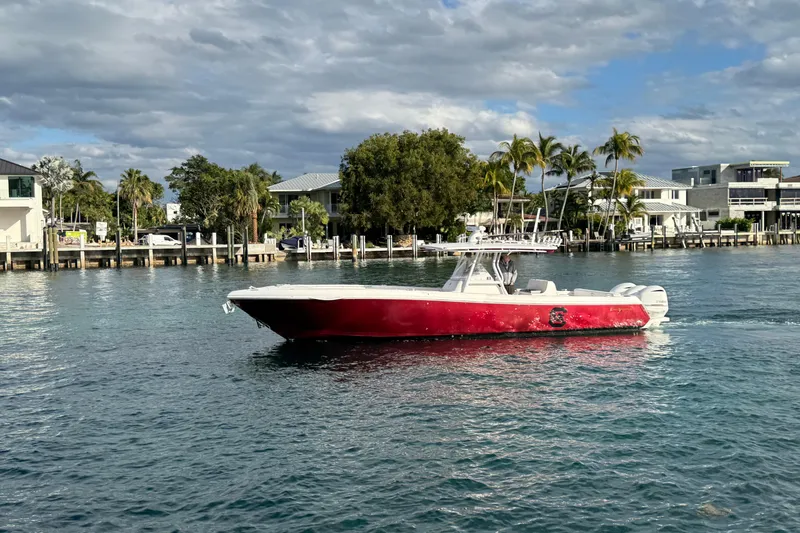 Slide: The Image of 2017 Intrepid 375 Center Console boat cruising on a sunny waterfront with palm trees. - 1