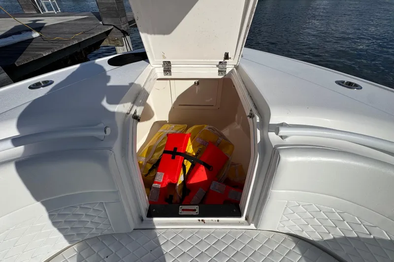 Slide: The Image of Open storage compartment on 2017 Intrepid 375 Center Console boat with life jackets inside. - 27