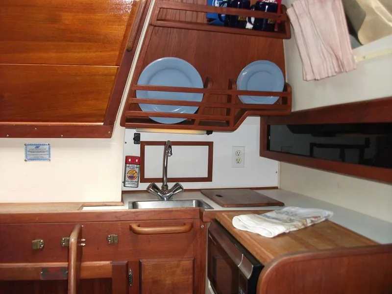 Slide: The Image of 1990 Catalina 27 yacht kitchen area with wooden cabinets. - 15