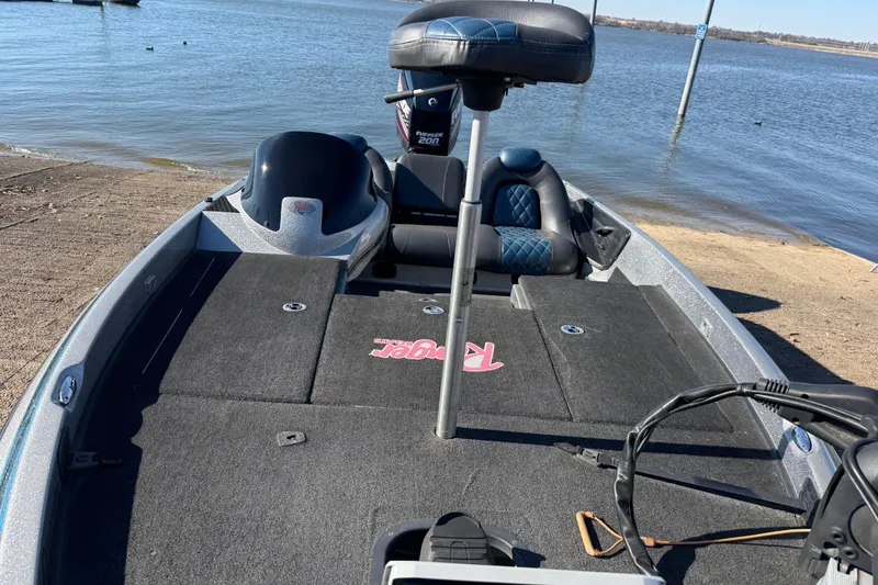 Slide: The Image of 2008 Ranger 198 VX boat on shore, featuring spacious deck and seating, near a calm lake. - 32