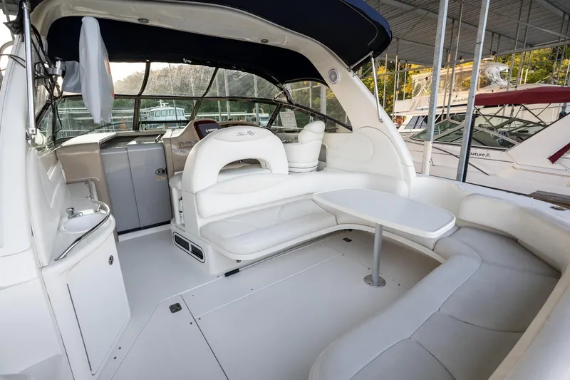 Slide: The Image of 2004 Sea Ray 380 Sundancer yacht interior with white seating and table in a marina. - 25