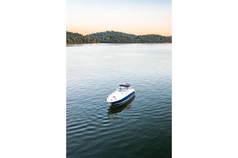 Slide: The Image of 2004 Sea Ray 380 Sundancer yacht on calm water with forested shoreline. - 29