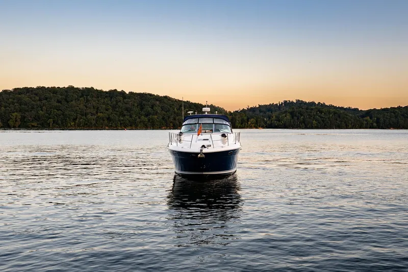 Slide: The Image of 2004 Sea Ray 380 Sundancer yacht on tranquil lake at sunset, surrounded by forested hills. - 3