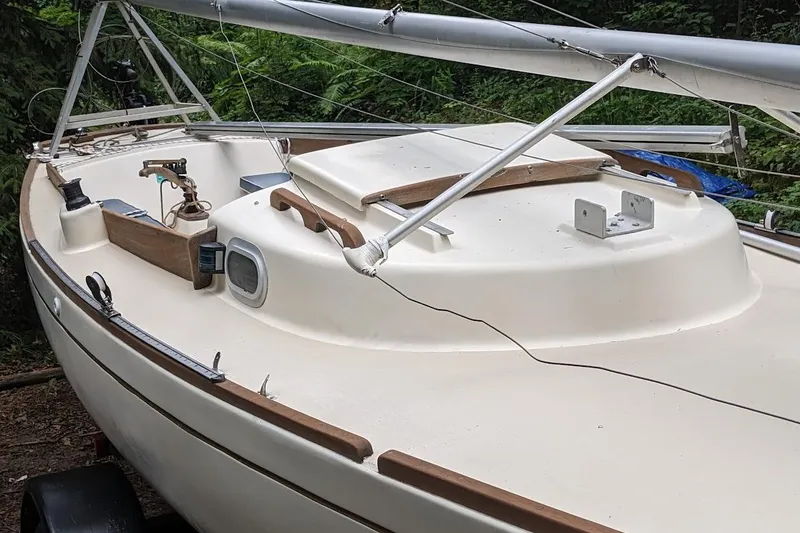Slide: The Image of 1981 McVay Bluenose sailboat with white deck and wooden trim, docked in a wooded area. - 16