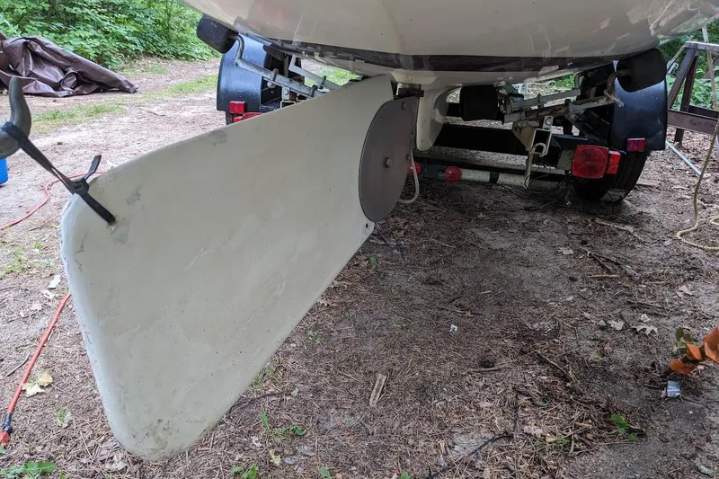 Slide: The Image of 1981 McVay Bluenose sailboat rudder on trailer in wooded area. - 2