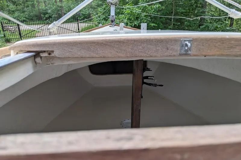 Slide: The Image of 1981 McVay Bluenose sailboat interior with wooden mast, surrounded by lush greenery. - 3