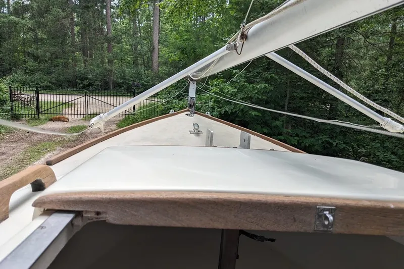 Slide: The Image of 1981 McVay Bluenose sailboat with mast, surrounded by lush greenery and a gated path. - 4