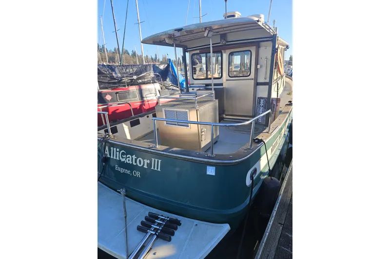 Slide: The Image of 1981 Nordic Tug Cricket boat docked at marina, front view with railing and winch. - 4