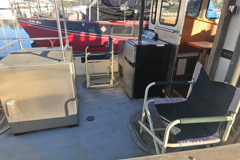 Slide: The Image of 1981 Nordic Tug Cricket boat deck with chairs, docked in a marina. - 13