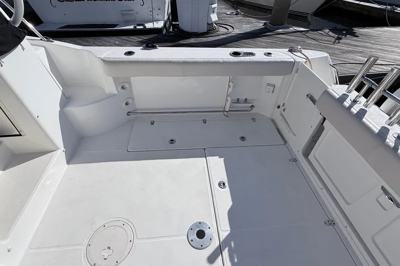 Slide: The Image of 2018 Boston Whaler 315 Conquest boat deck with storage compartments and rod holders. - 25