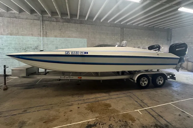 Slide: The Image of 1990 Skater 24 boat with blue accents in a concrete garage. - 2