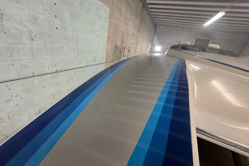 Slide: The Image of 1990 Skater 24 boat with blue stripes in a garage. - 26