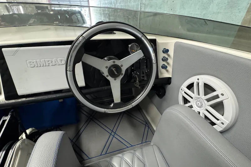 Slide: The Image of Interior of a 1990 Skater 24 boat with steering wheel and Simrad display. - 29