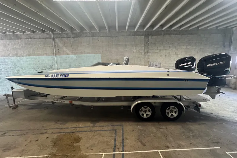 Slide: The Image of 1990 Skater 24 boat with twin Mercury 300XS engines on a trailer in a garage. - 4