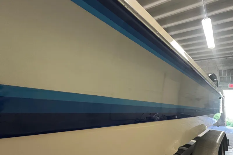 Slide: The Image of 1990 Skater 24 boat with blue stripes in a garage setting. - 7