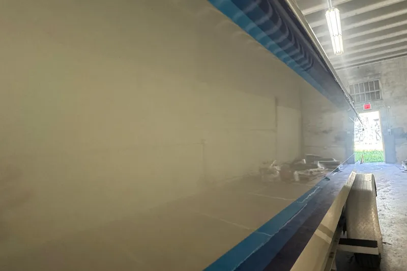 Slide: The Image of Polished side of a 1990 Skater 24 boat in a workshop setting. - 8