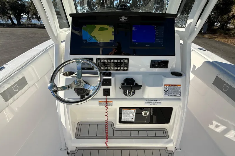 Slide: The Image of 2024 Sea Fox 288 Commander boat dashboard with steering wheel and navigation screens. - 11
