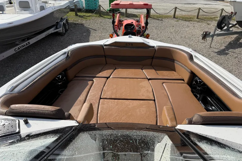 Slide: The Image of 2024 Yamaha 275SDX boat interior with brown leather seating, parked outdoors. - 11
