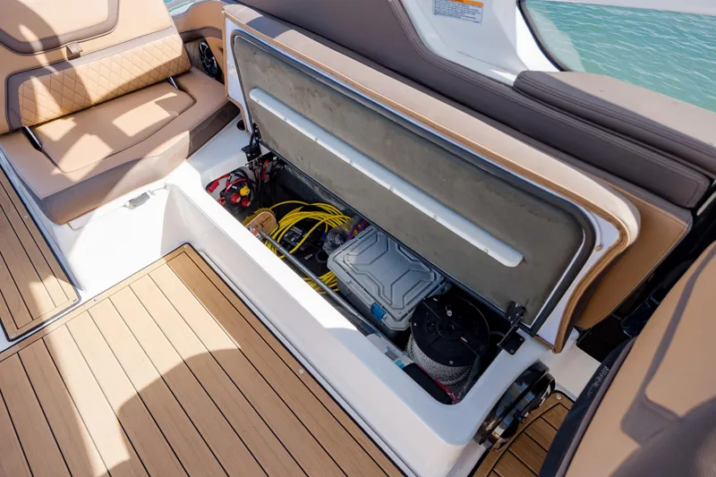 Slide: The Image of 2024 Yamaha Boats 275SD storage compartment with seating and equipment, on a sunny day. - 29