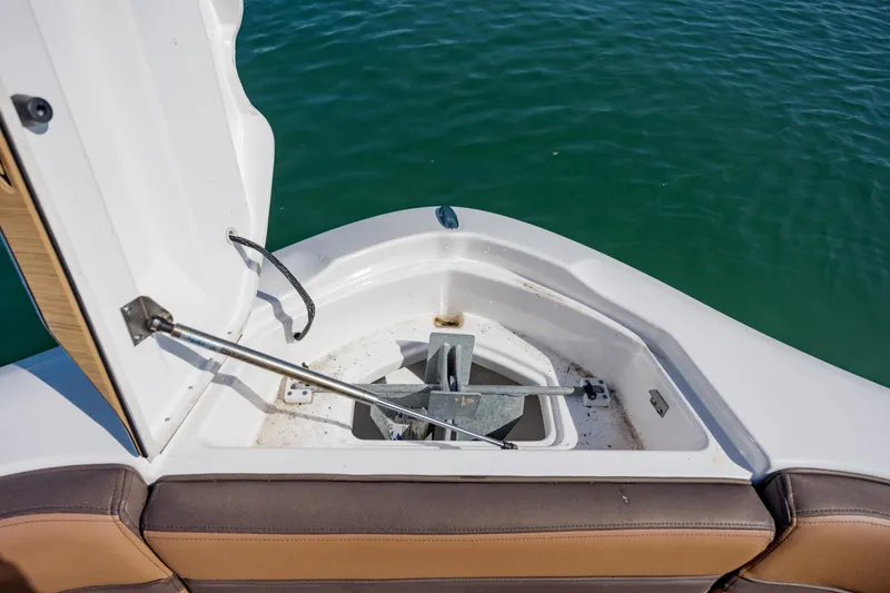 Slide: The Image of 2024 Yamaha Boats 275SD anchor compartment open, revealing anchor storage by the water. - 33