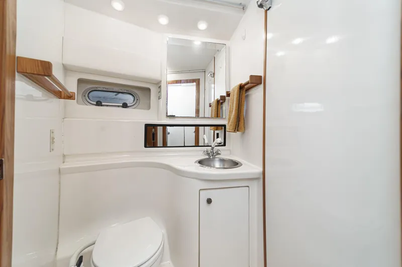 Slide: The Image of 1998 Bayliner 3988 Motoryacht bathroom with sink, toilet, mirror, and porthole window. - 11