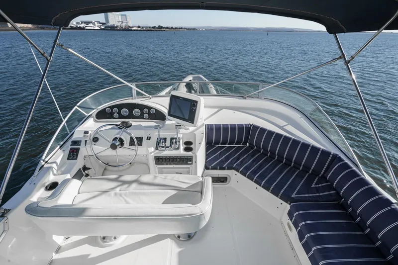 Slide: The Image of 1998 Bayliner 3988 Motoryacht helm with striped seating, overlooking calm waters. - 2