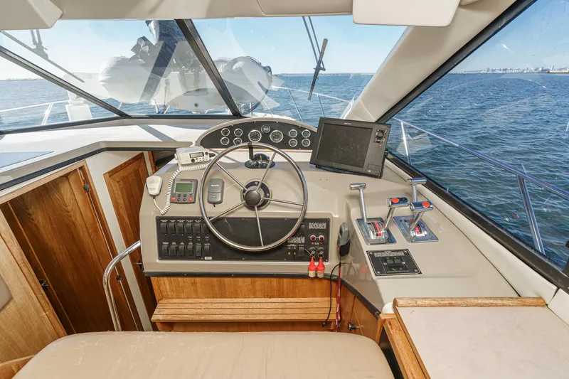 Slide: The Image of 1998 Bayliner 3988 Motoryacht helm with steering wheel, controls, and navigation equipment on open water. - 26