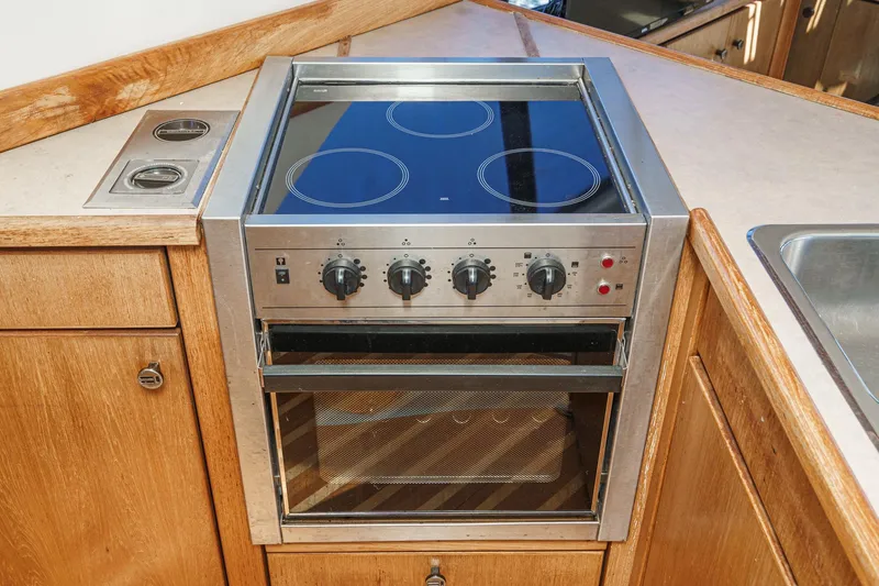 Slide: The Image of 1998 Bayliner 3988 Motoryacht kitchen with electric stove and oven, wooden cabinetry. - 30