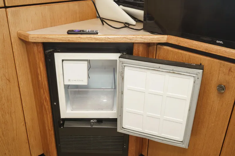 Slide: The Image of Open mini fridge in 1998 Bayliner 3988 Motoryacht interior, wooden cabinetry, remote on counter. - 35