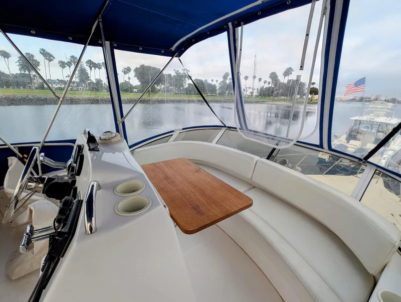 Slide: The Image of 1999 Silverton 351 Sedan Cruiser interior with helm, seating, and table, overlooking marina. - 11