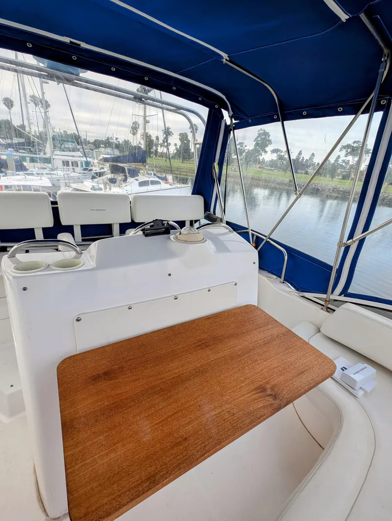 Slide: The Image of 1999 Silverton 351 Sedan Cruiser interior with blue canopy and wooden table. - 12