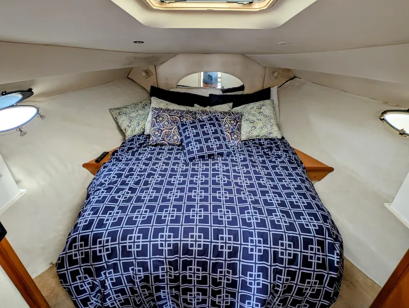 Slide: The Image of 1999 Silverton 351 Sedan Cruiser cabin with patterned bedding and porthole windows. - 4