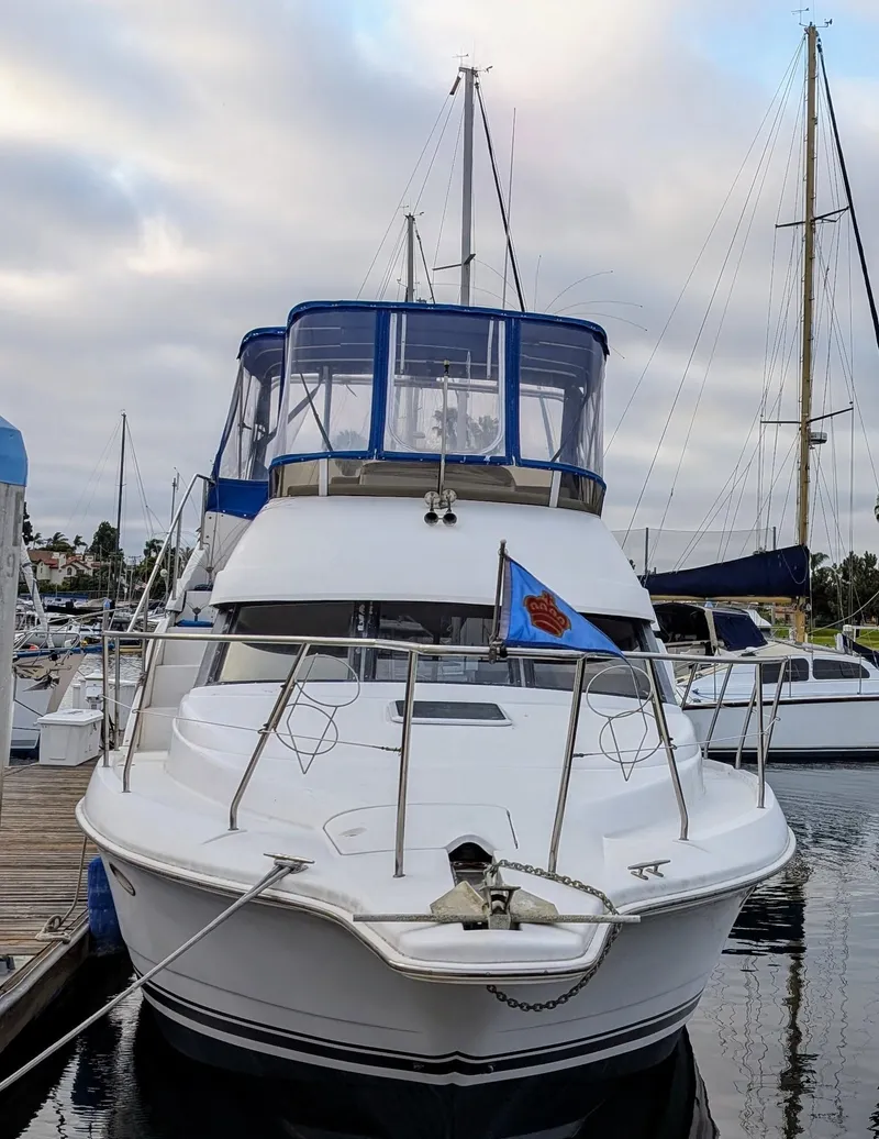 Slide: The Image of 1999 Silverton 351 Sedan Cruiser docked at marina, featuring blue canopy and sleek design. - 7
